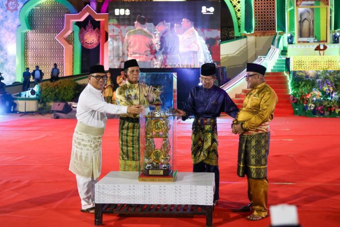 
					Gubernur Kepri Ansar Ahmad bersama Wagub Kepri sekaligus Ketua LPTQ Nyanyang Haris Pratamura menyerahkan tropi bergilir MTQ Kepulauan Riau kepada Wali Kota Tanjungpinang Lis Darmansyah pada pembukaan MTQ XII Tingkat Provinsi Kepri, Sabtu (4/7/2026) malam. Sebelumnya tropi diterima dari Wali Kota Batam Amsakar Achmad sebagai juara umum MTQ XI tahun 2025. 