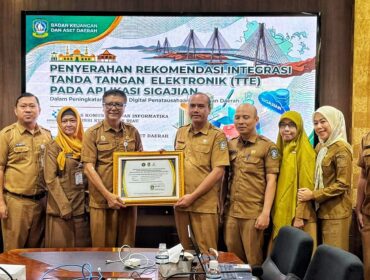 Sekretaris Diskominfo Kepri, James Simon Pattikawa menyerahkan Piagam Pengesahan Integrasi TTE Aplikasi SIGAJIAN kepada Kepala Bidang Perbendaharaan dan Pengelolaan Kas Daerah BKAD Kepri I Gede Sukanta, Selasa (4/8/2026).