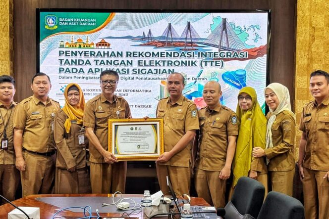 
					Sekretaris Diskominfo Kepri, James Simon Pattikawa menyerahkan Piagam Pengesahan Integrasi TTE Aplikasi SIGAJIAN kepada Kepala Bidang Perbendaharaan dan Pengelolaan Kas Daerah BKAD Kepri I Gede Sukanta, Selasa (4/8/2026).